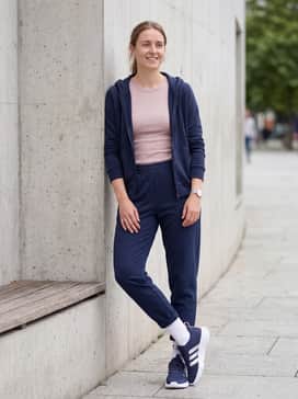 Navy joggers and a matching zip-up hoodie layered over a pale pink crop top to highlight the shoe's subtle color accents.