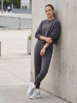 Charcoal grey tapered joggers worn with a matching cropped sweatshirt to create a sleek, monochromatic loungewear set perfect for travel.