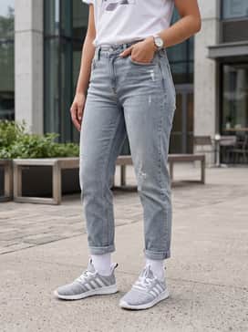 Light-wash distressed boyfriend jeans cuffed at the ankle to show off the shoe's profile, paired with a tucked-in white graphic tee and a minimalist silver watch.