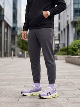 A sleek athleisure look consisting of charcoal grey tapered joggers, a fitted black tech-fleece hoodie, and high-performance no-show socks.