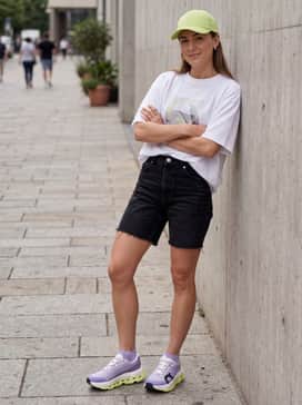 Cloudmonster 3 Hyper – A modern streetwear outfit with high-waisted black biker shorts, an oversized white graphic t-shirt, and a lime green cap to highlight the citron sole.