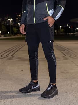Cloudmonster Lumos – A nighttime visibility ensemble consisting of reflective running leggings, a neon-accented base layer, and a lightweight silver windbreaker.