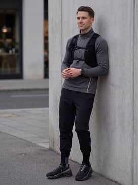Cloudmonster Lumos – A modern athleisure outfit pairing tapered technical joggers with a seamless knit quarter-zip and a minimalist hydration vest.
