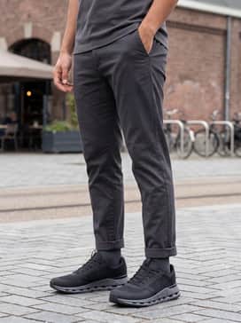 Cloudnova Form 2 Tt – Slim-fit charcoal denim jeans with a simple white crewneck sweater and an olive green utility vest for a balanced casual aesthetic.