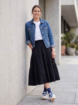 Cloudnova Moon – A black tiered midi skirt with a crisp white graphic tee and a denim jacket to create a balanced feminine-meets-sporty aesthetic.