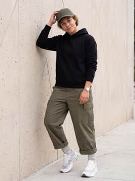 Olive green cargo pants with a minimalist black hoodie and a structured baseball cap, perfect for a utilitarian streetwear aesthetic.