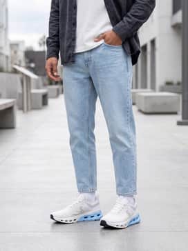A clean streetwear ensemble consisting of light-wash athletic fit denim jeans, a premium heavy-weight white boxy tee, and a charcoal grey unbuttoned flannel shirt.