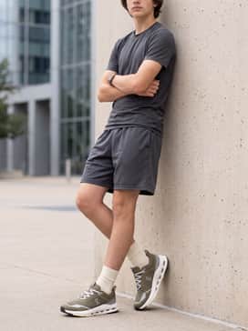 Athletic mesh shorts in charcoal grey combined with a moisture-wicking t-shirt in pale yellow to highlight the subtle yellow accents on the shoe's outsole.