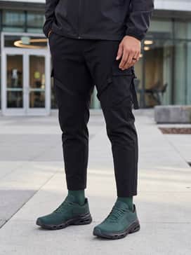 Urban techwear ensemble featuring tapered black cargo joggers with utility straps and a sleek matte black windbreaker.