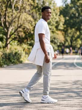 Light grey slim-fit sweatpants, a crisp white oversized hoodie, and a minimalist black baseball cap for a clean, monochromatic casual vibe.