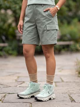 For warmer weather, style them with sage green cargo shorts, a breathable white racerback tank top, and thick tan crew socks pulled up to showcase the high-top silhouette.