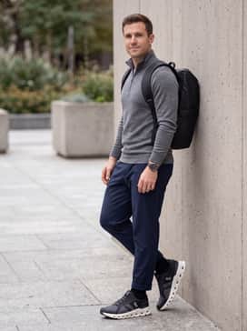 A refined active-casual ensemble with navy athletic-fit chinos, a grey merino wool quarter-zip pullover, and a sleek waterproof backpack.