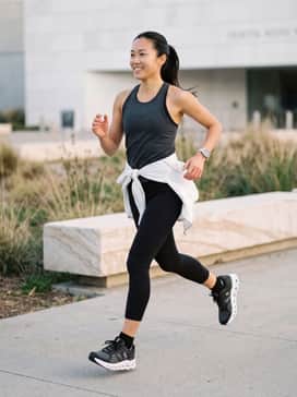 Pair with high-waisted black compression leggings, a seamless charcoal grey racerback tank, and a lightweight white windbreaker for a sleek, high-performance running look.