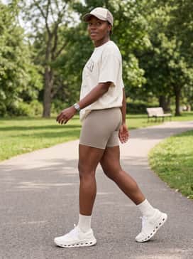 Relaxed-fit biker shorts in a neutral taupe shade worn with a vintage-style graphic oversized t-shirt and a canvas baseball cap for a trendy, casual street-style vibe.