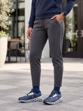 Technical charcoal grey joggers paired with a fitted navy tech-fleece hoodie and a matching grey performance baseball cap for a streamlined athletic look.