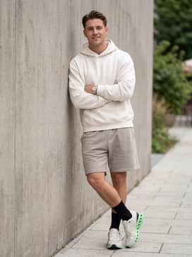 Cloudsurfer 2 – An effortless post-gym outfit with light grey jersey shorts, an oversized off-white graphic hoodie, and black crew-length athletic socks for a street-inspired vibe.