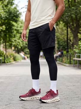 A classic gym ensemble with black high-ventilation mesh shorts, a fitted cream-colored performance tank top, and high-performance white crew socks.