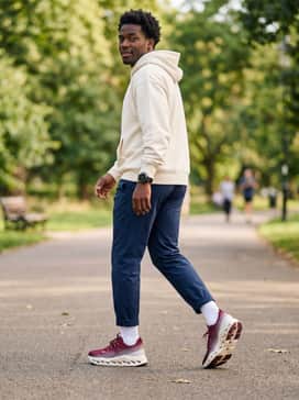 Cloudsurfer Max – A post-run recovery style including navy blue relaxed-fit tapered track pants, an oversized white premium cotton hoodie, and a sleek matte black sports watch.