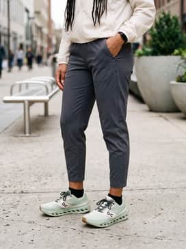 Cloudsurfer Next Z5 – Charcoal grey tapered tech joggers paired with a lightweight cream windbreaker and a black moisture-wicking headband.