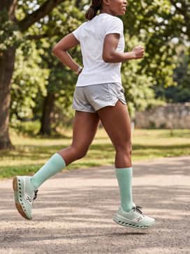 Reflective silver running shorts matched with a mint green sports bra and a white mesh training vest for visibility and breathability.