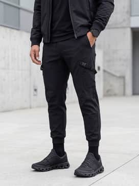 Cloudswift 4 Ad – A sleek techwear aesthetic consisting of tapered black cargo joggers with tactical buckle details, an oversized graphic white tee, and a matte black utility bomber jacket.