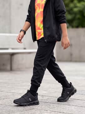 Black moisture-wicking joggers paired with a vibrant neon graphic tee and a lightweight windbreaker for a dedicated sports practice look.