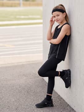 Cloudswift Kids – Athletic leggings worn with a breathable jersey tank top and a matching headband for a focused track-and-field training session.