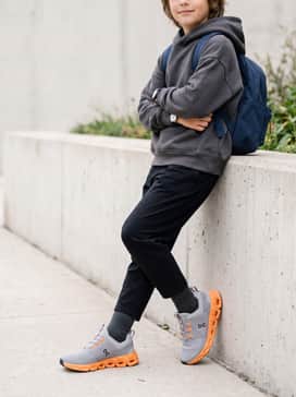 Black athletic leggings worn with a charcoal grey oversized hoodie and a small backpack for an easy transition from school to after-school sports.