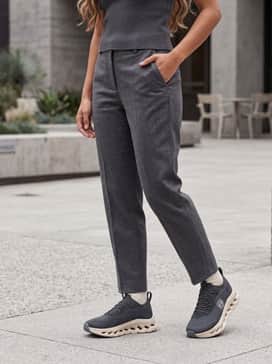 Charcoal grey tapered joggers with a matching oversized hoodie and a cropped sand-colored puffer vest for a high-end, tonal athleisure ensemble.