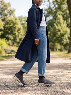 Cloudtilt Loewe – Straight-leg raw denim jeans cuffed at the ankle to show off the shoe's profile, worn with a white button-down shirt and a classic navy trench coat.