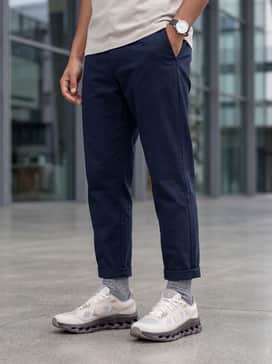 Tapered navy chinos with a rolled cuff, paired with a high-quality white pima cotton t-shirt and a structured olive utility jacket.