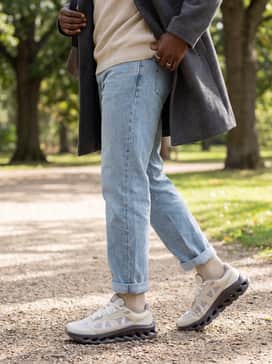 Light-wash straight-leg denim jeans complemented by a textured oatmeal crewneck sweater and a minimalist charcoal overcoat for a polished weekend look.