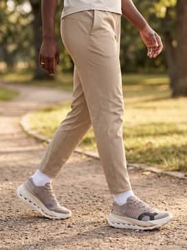 Sand-colored tapered technical joggers, a cream-colored moisture-wicking hoodie, and a matching performance cap for a cohesive post-trail recovery look.