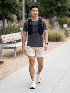 A pair of 5-inch split running shorts in charcoal grey, a moisture-wicking sage green tank top, and a black hydration racing vest for a professional trail setup.