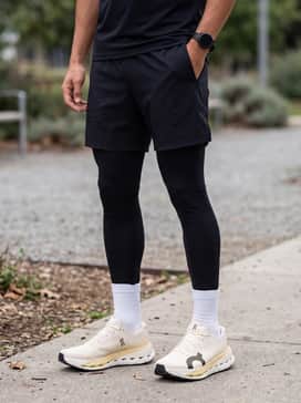 Cloudultra Pro – Tapered black technical joggers, a cream-colored compression base layer, and a neon-accented lightweight windbreaker that mirrors the shoe's highlights.
