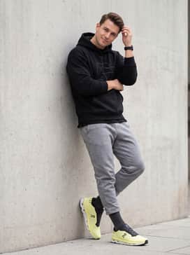 Heather grey tech-fleece shorts combined with a black oversized graphic hoodie and high-performance crew socks for a contemporary streetwear aesthetic.