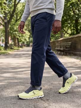 Cloudzone – Dark navy chinos worn with a light grey cashmere sweater and a minimalist navy mac coat, blending professional polish with athletic comfort for a smart-casual office vibe.