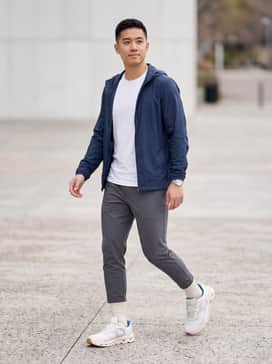 Tapered charcoal joggers paired with a moisture-wicking white performance tee and a lightweight navy blue windbreaker for a sleek athletic look.