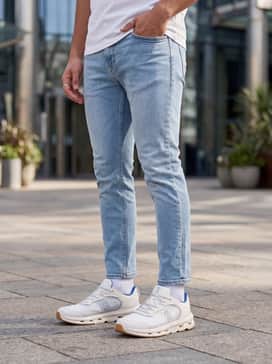 Light wash slim-fit denim jeans worn with a cream-colored knit polo and a tan suede bomber jacket to transition from a casual lunch to a city stroll.