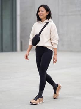 Cloudzone – High-waisted black leggings paired with an oversized cream-colored hoodie and a sleek black crossbody bag for a classic athleisure look.