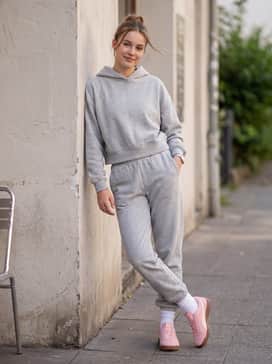 Oversized grey heather joggers and a matching cropped hoodie with white crew socks for a trendy, comfortable 'clean girl' ensemble.