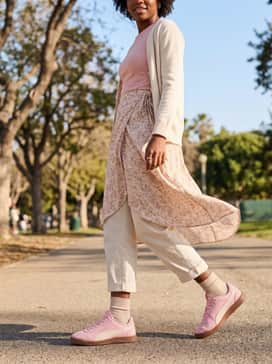 Tailored white wide-leg trousers and a beige linen button-down shirt left open over a soft pink camisole to complement the shoe's gold foil accents.