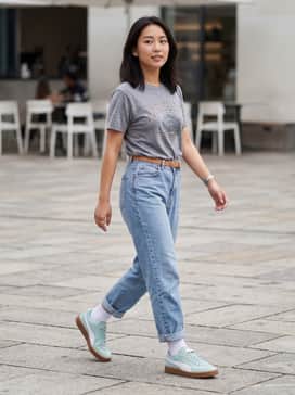 Light-wash mom jeans paired with a vintage-style graphic tee tucked in, accessorized with a tan leather belt to complement the gum sole.