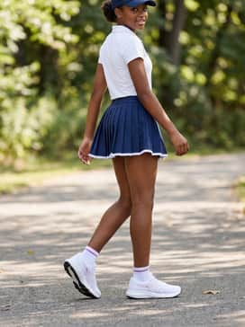 Contend 9 Grade School – A navy blue tennis skirt or skort matched with a white polo shirt and a sporty baseball cap, perfect for a clean and preppy athletic appearance.