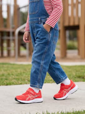 Classic denim overalls worn over a red-and-white horizontal striped long-sleeve shirt to pull the shoe color into the outfit.