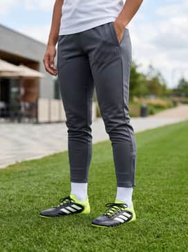 Copa Pure 3 Elite Firm Ground Cleats – A streamlined training ensemble consisting of a charcoal grey quarter-zip tech top, tapered black training joggers with ankle zips, and white compression gear.
