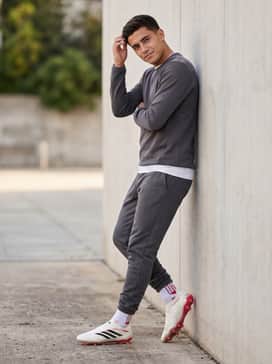 A modern warm-up outfit pairing a sleek charcoal grey tracksuit with white athletic base layers and high-performance grip socks to ensure stability inside the laceless boot.