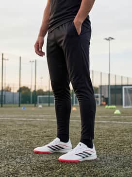 A sleek charcoal grey quarter-zip training top paired with tapered black track pants that feature ankle zips to highlight the shoe silhouette.