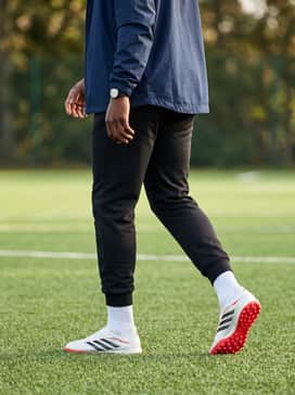 A thermal base-layer compression shirt worn under a lightweight navy windbreaker, styled with matte black athletic leggings for cold-weather turf sessions.