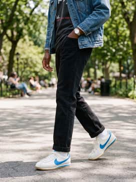 Cortez Leather – Black slim-cut jeans paired with a faded graphic band tee and an oversized vintage denim jacket for an effortless streetwear aesthetic.